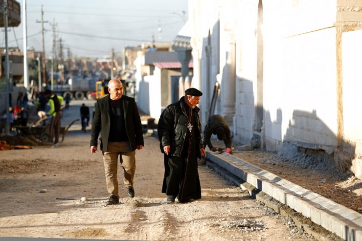 Um padre observa trabalhadores consertando uma rua destruída durante confrontos contra militantes do Estado Islâmico em Qaraqosh, Iraque, em 23 de fevereiro.